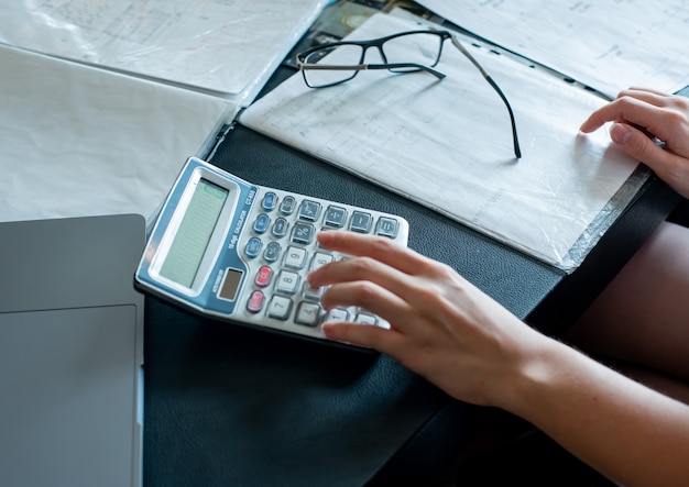 close-up-view-female-hands-doing-calculations-documents-with-glasses-office-desk-working-process-office-concept_141793-21242